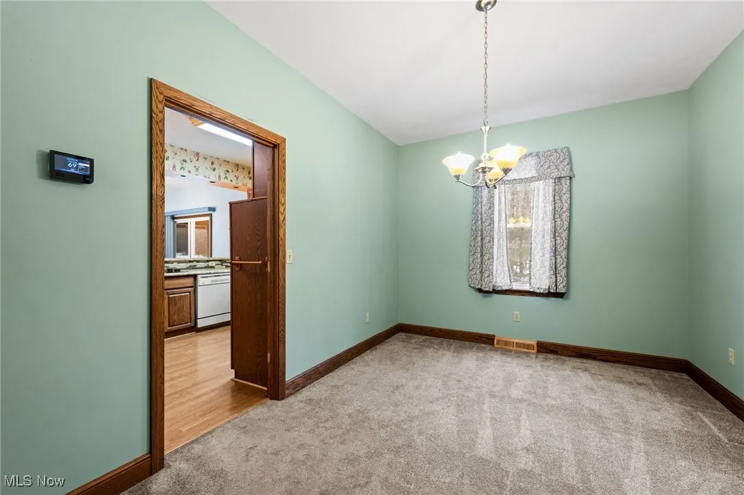 Unfurnished dining area with carpet and a chandelier