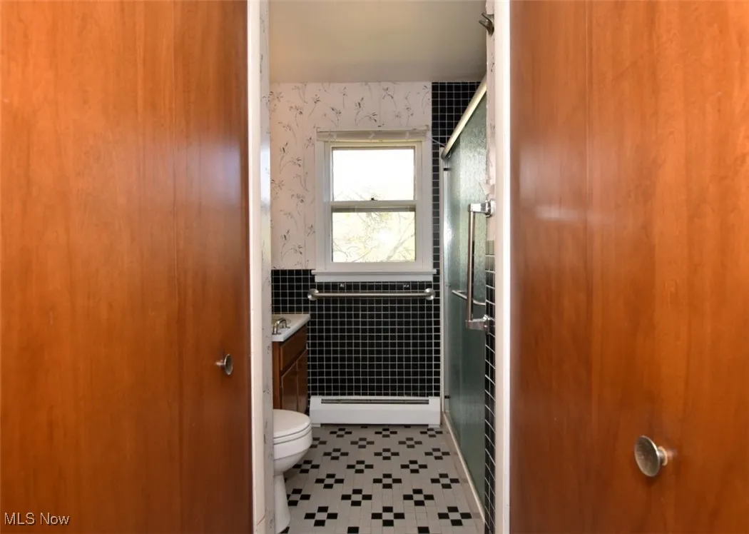 First floor full bathroom attached to the den/office/5th bedroom with two large closets, low entry shower, updated faucet, light and glass shower door.