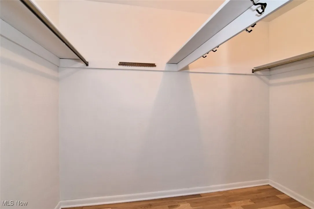 Walk in closet with hardwood floors.