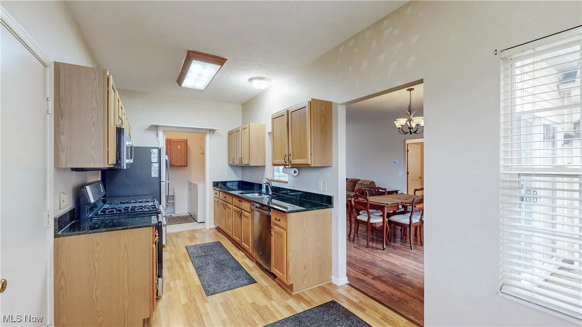 Eat-in, Galley-style Kitchen with stainless steel appliances, oak cabinets, granite countertops, light wood-style floors and laundry room is beyond