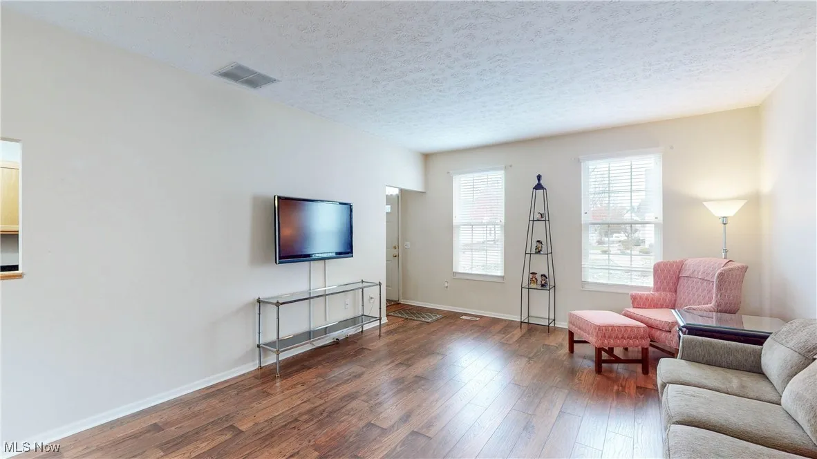 View from DR into Living room with dark wood-style flooring and a textured ceiling
Mounted TV stays w/unit