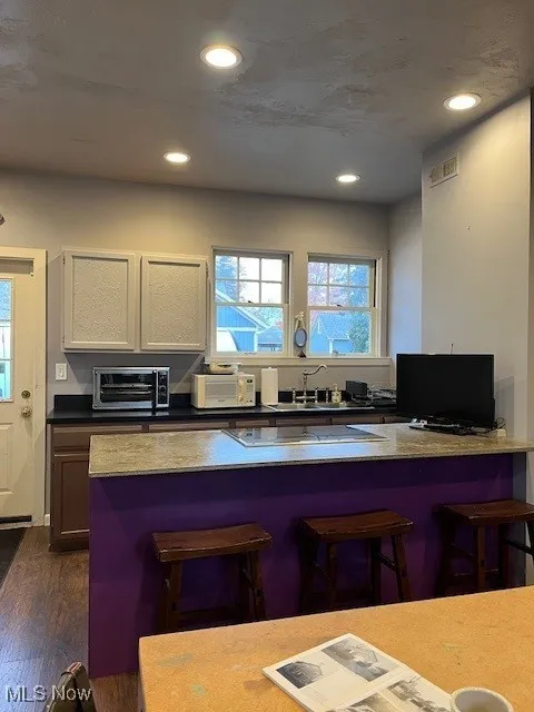 Kitchen featuring newer center island, plenty of natural light, recessed lighting, newer foors and cabinets, exterior entrance.