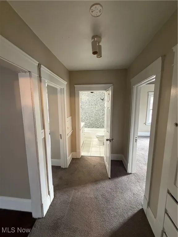 Hall featuring dark carpet and baseboards