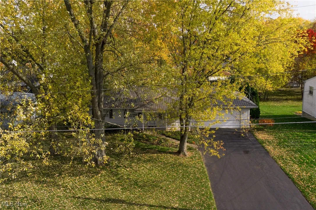 View of side of property with asphalt driveway, a yard, and a garage