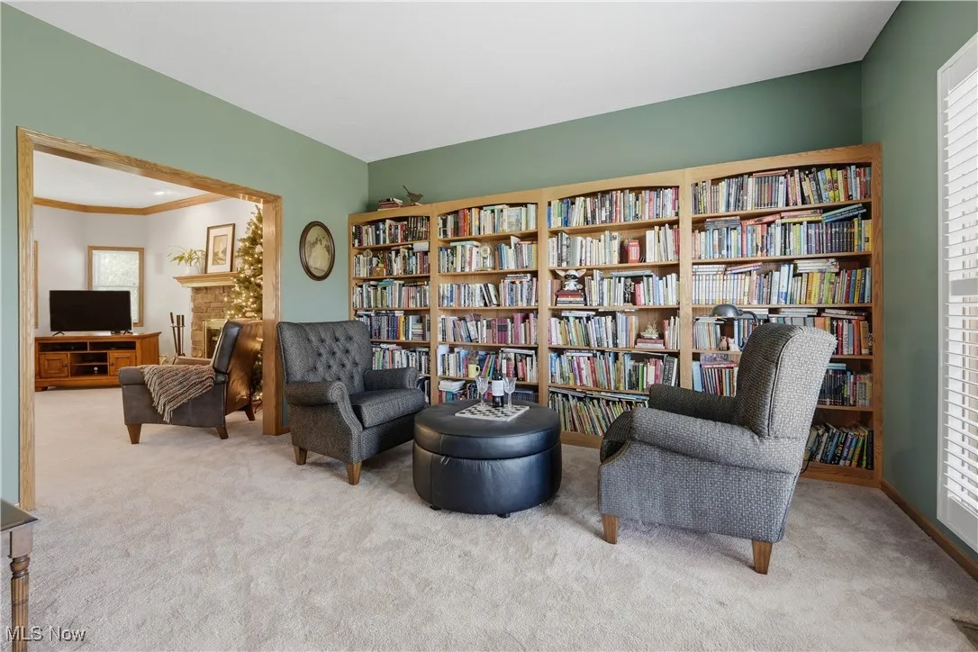 Living area with light colored carpet, ornamental molding, and bookshelves