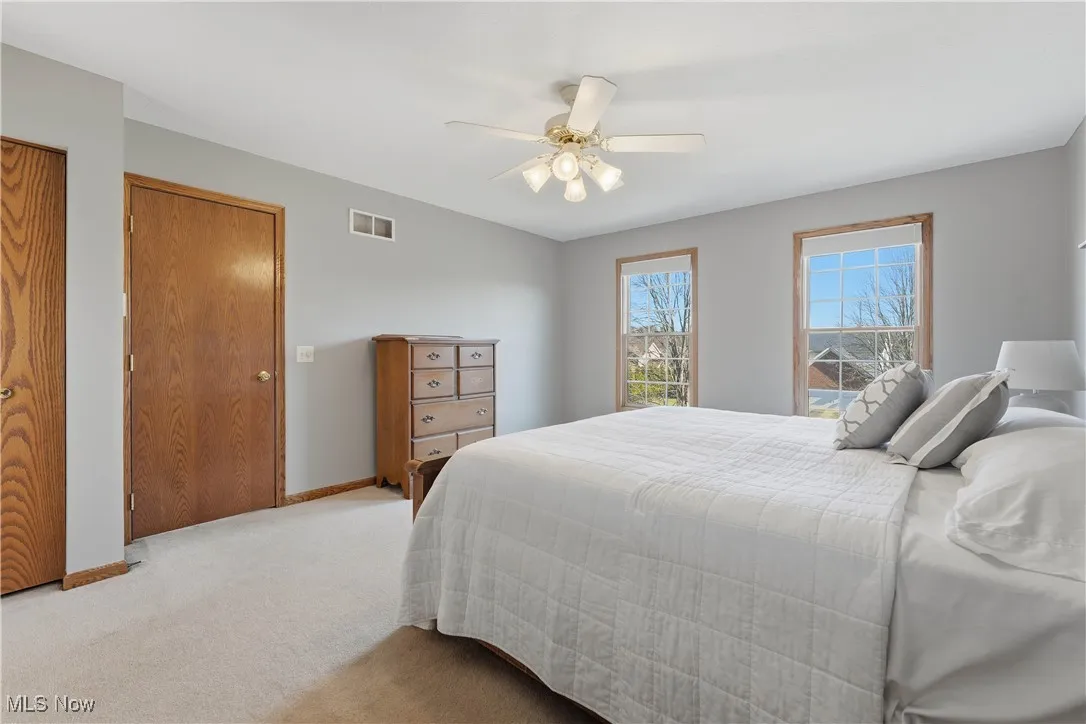 Carpeted bedroom with a ceiling fan and baseboards