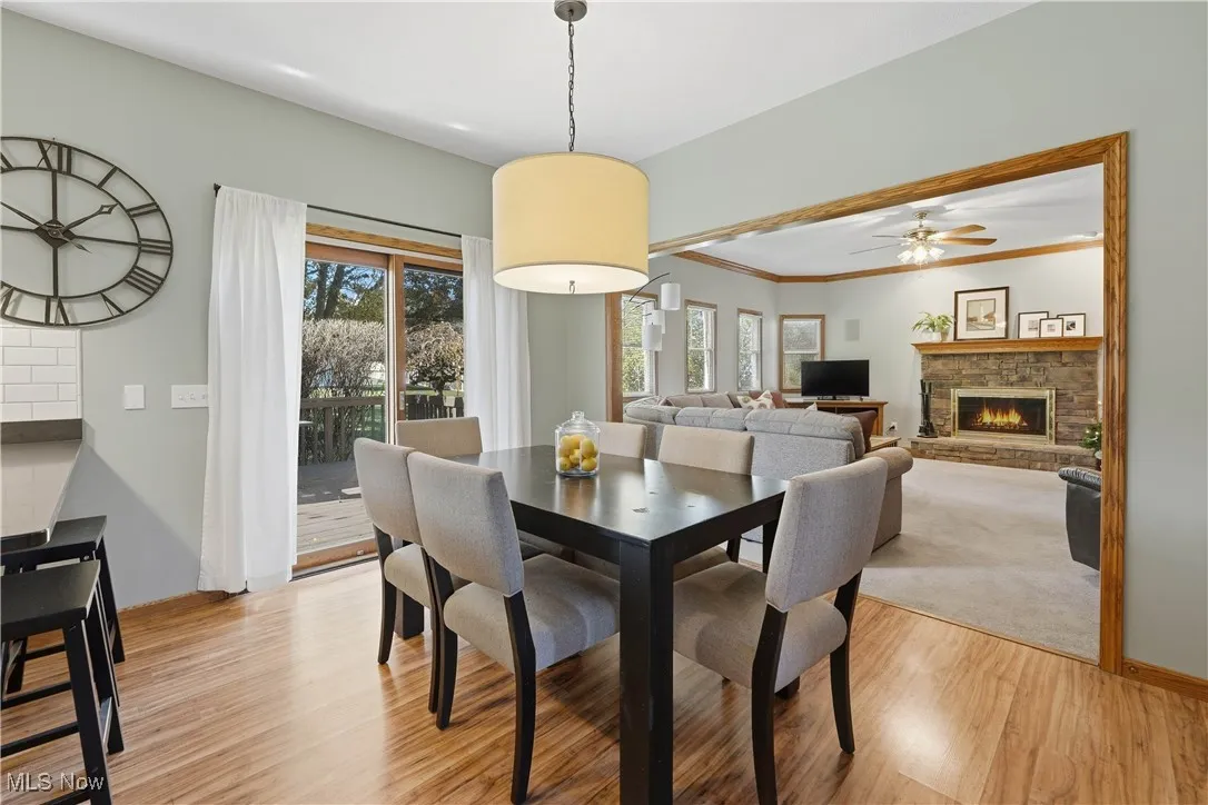 Dining area with a fireplace, light wood finished floors, healthy amount of natural light, and a ceiling fan