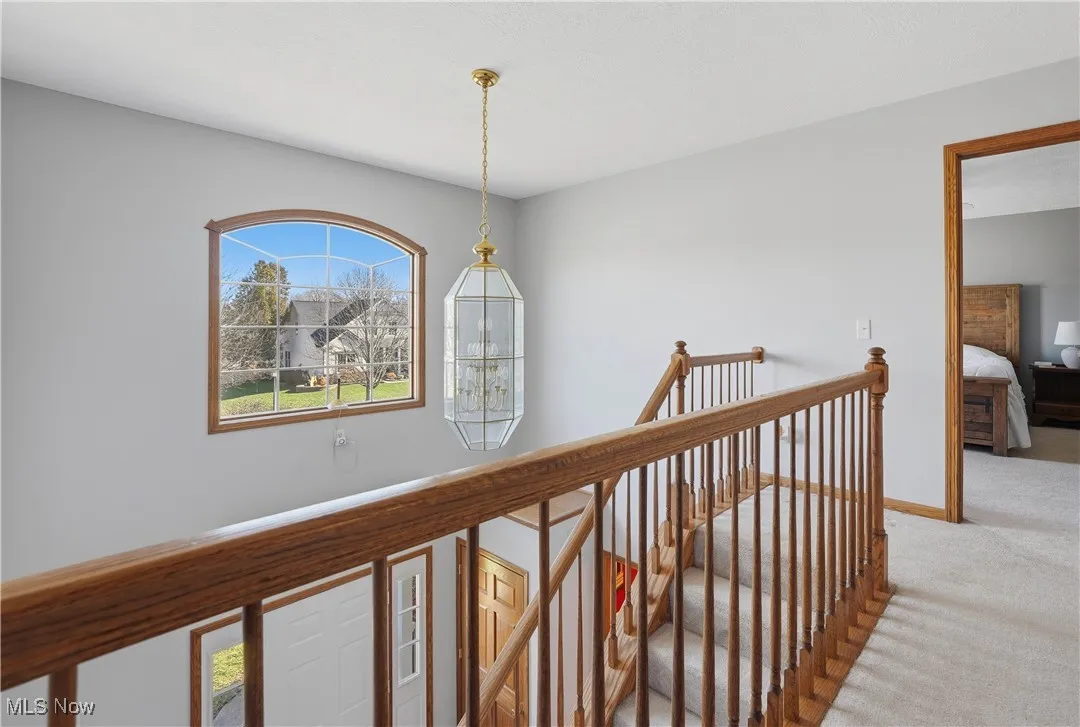 Hall featuring a chandelier, an upstairs landing, and light carpet