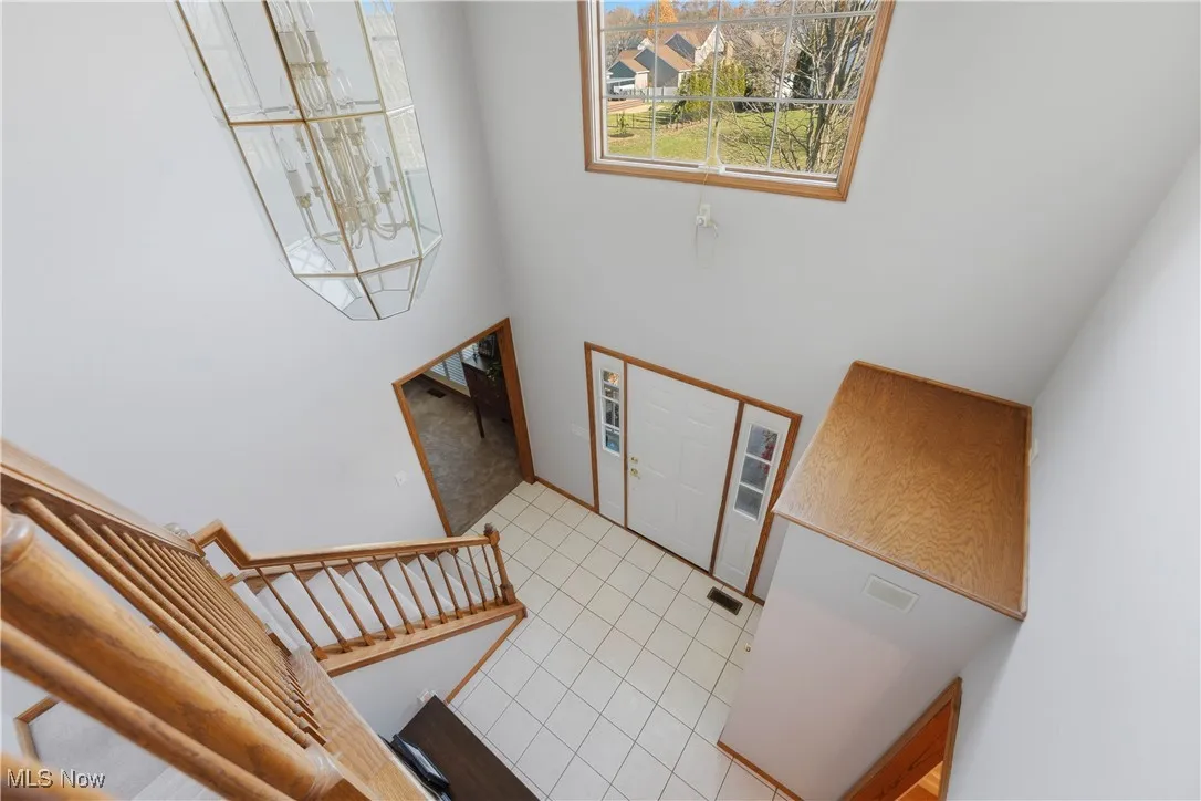 Foyer with light tile patterned floors, a high ceiling, a chandelier, and stairs