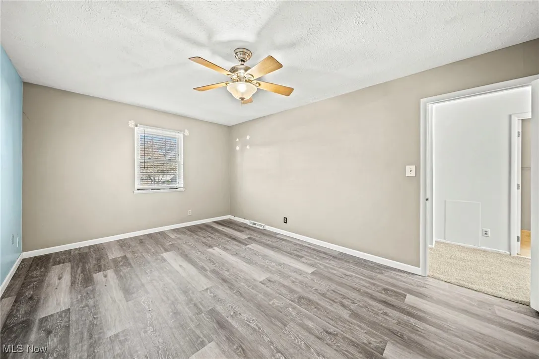 Spare room featuring light wood-style floors, a textured ceiling, and a ceiling fan