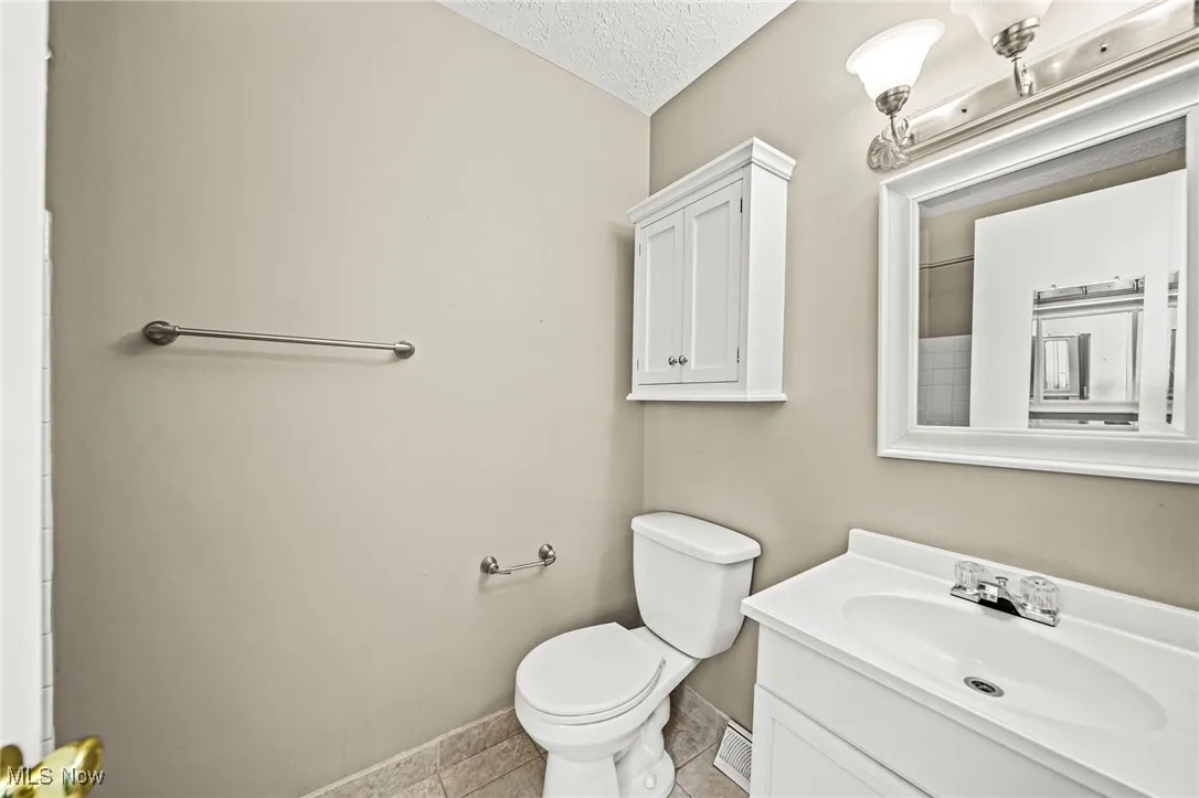 Full bathroom with light tile patterned flooring, a textured ceiling, and vanity