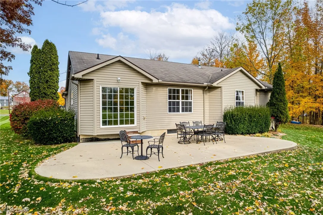 Back of house with a patio area, a lawn, and a shingled roof