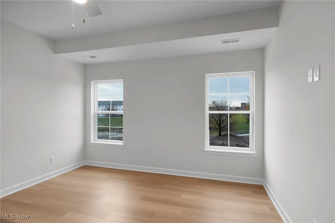 Empty room with light wood-type flooring, healthy amount of natural light, and ceiling fan
