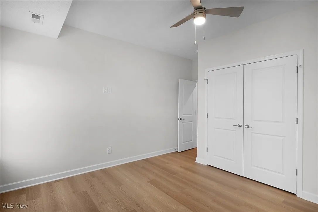 Unfurnished bedroom featuring light wood finished floors, a closet, and ceiling fan