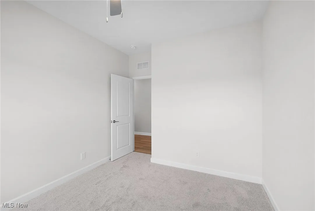 Carpeted spare room with baseboards and a ceiling fan