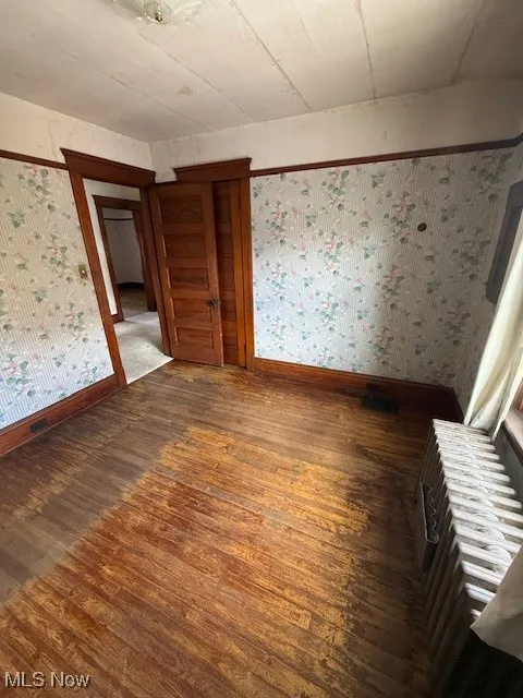 Room featuring wallpapered walls and dark wood-style floors