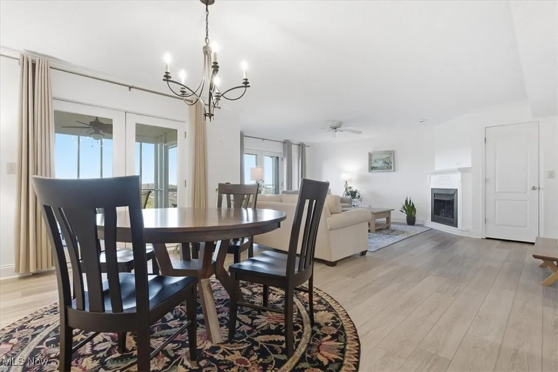 Dining area featuring ceiling fan, light wood-style floors, a fireplace, and a chandelier