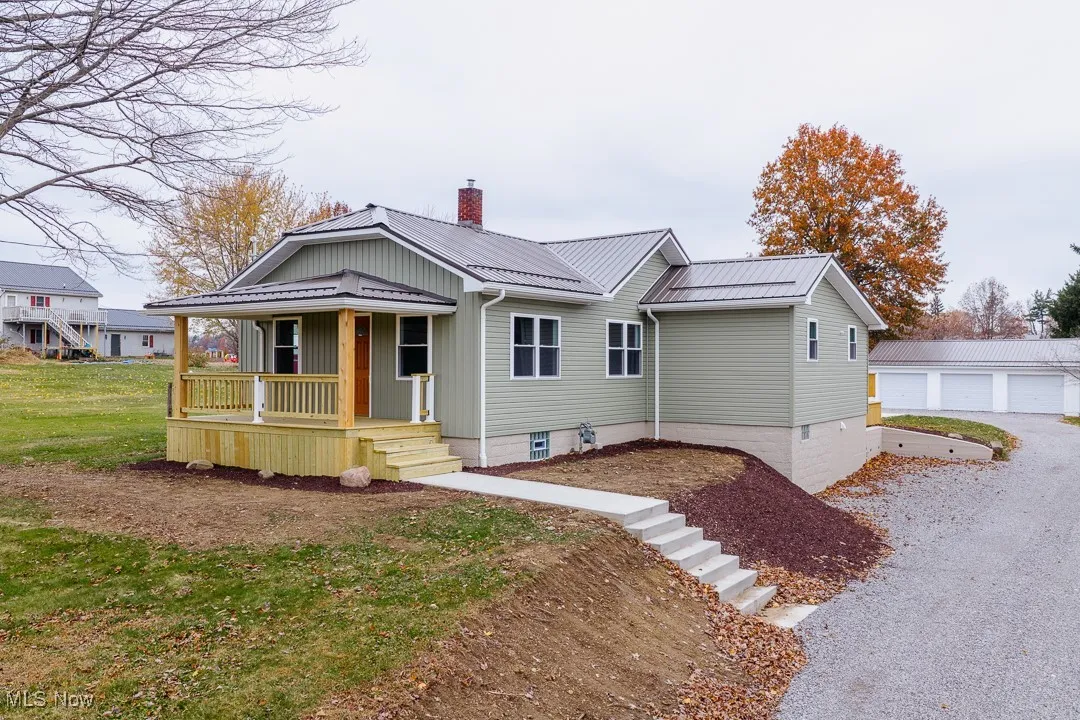 View of front of home featuring a chimney, a metal roof, covered porch, and an outdoor structure