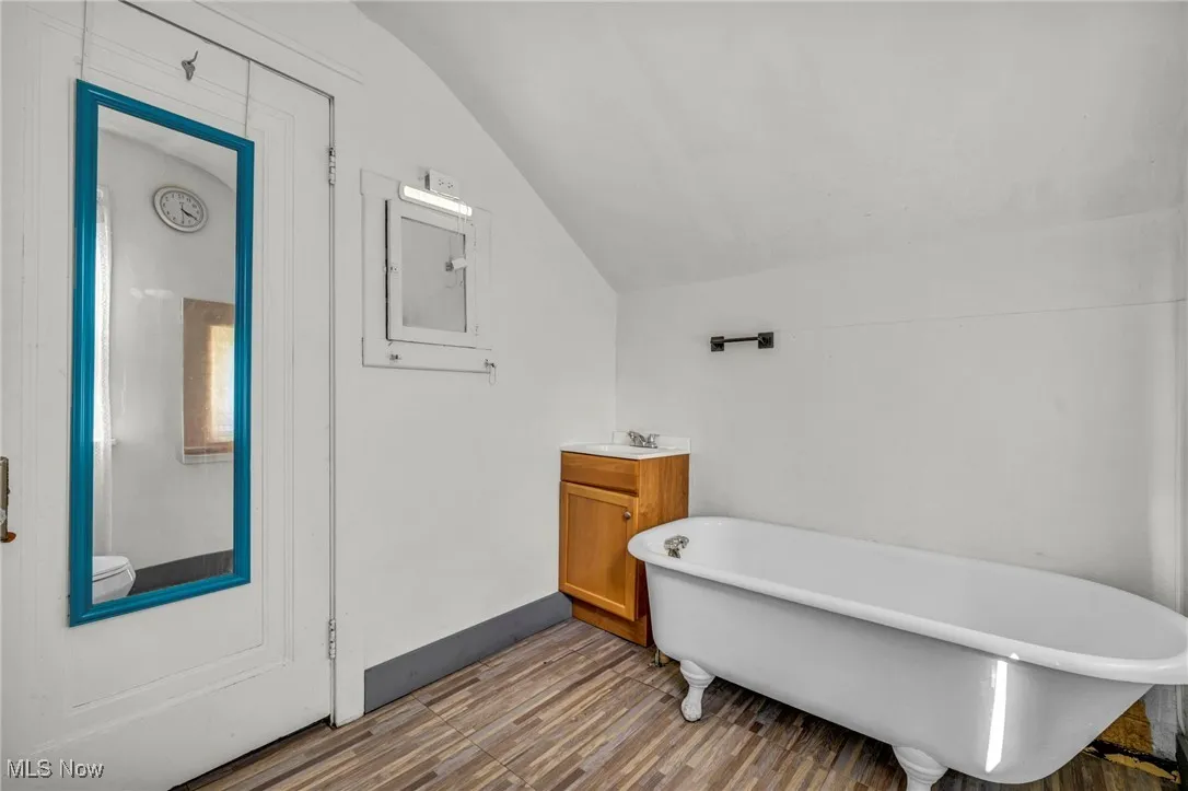Bathroom with lofted ceiling, a freestanding bath, vanity, and wood finished floors