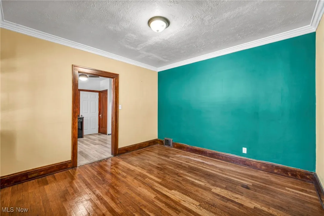 Spare room with wood-type flooring, ornamental molding, and a textured ceiling