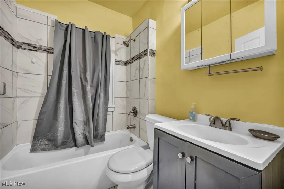 Bathroom with shower / bath combination with curtain and vanity