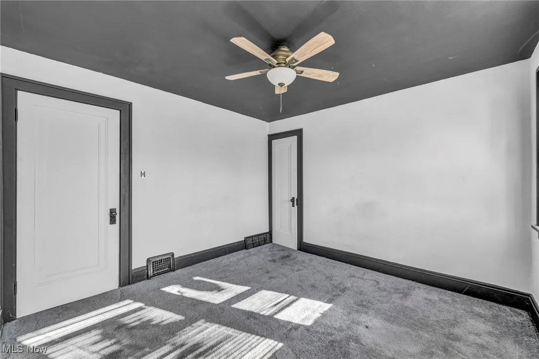 Carpeted empty room with a ceiling fan and baseboards