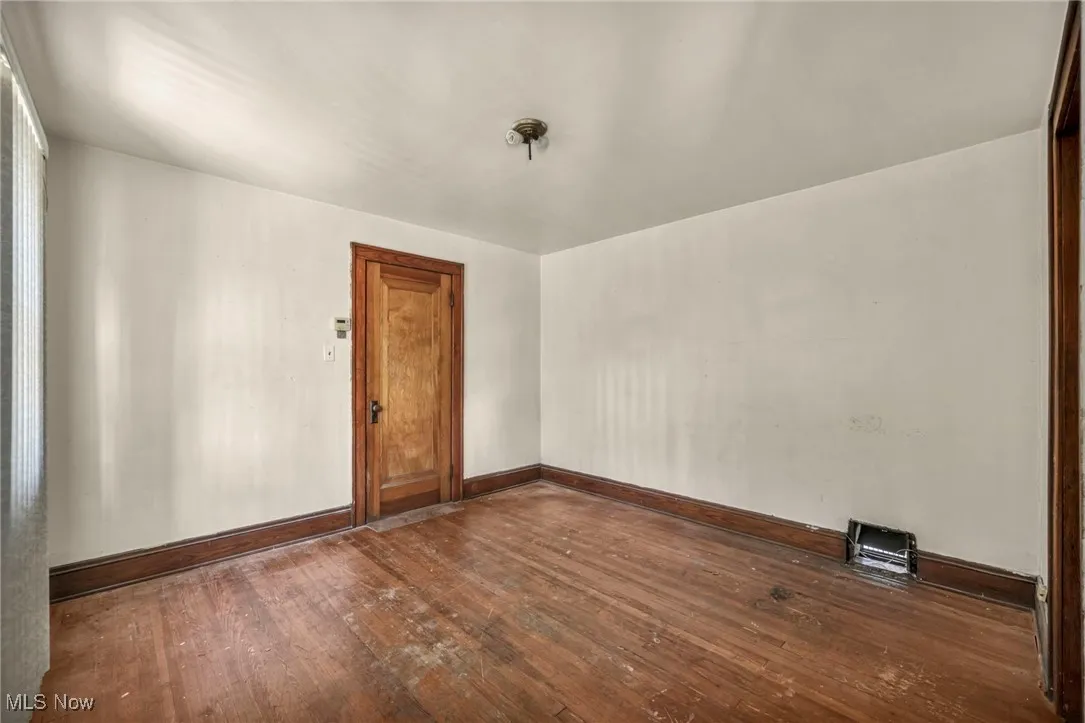 Spare room featuring dark wood-style flooring and baseboards