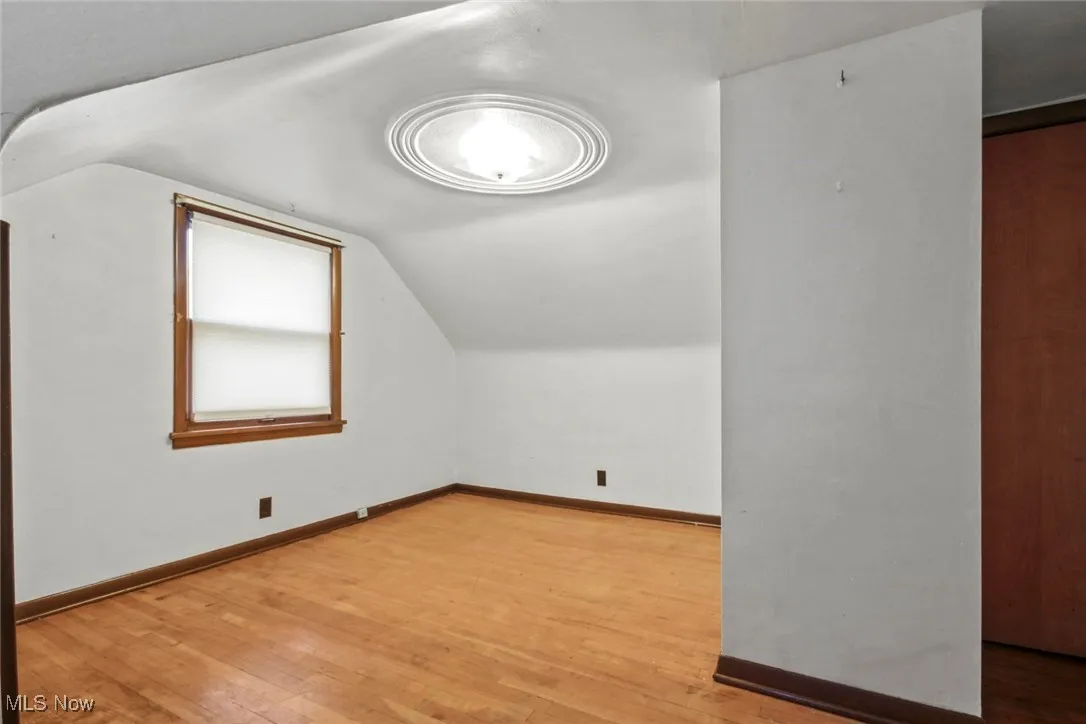 Bonus room with light wood-style flooring and lofted ceiling