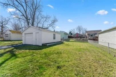 View of yard with an outdoor structure, a detached garage, driveway, and fence