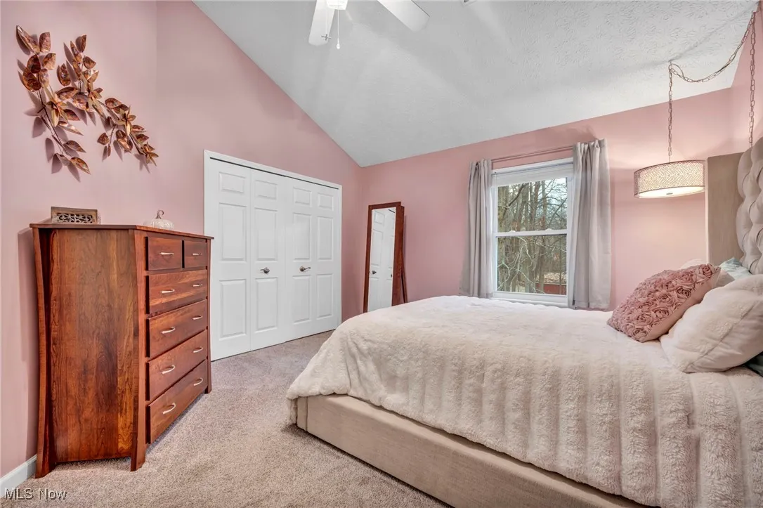 Bedroom with light carpet, a closet, a ceiling fan, and high vaulted ceiling