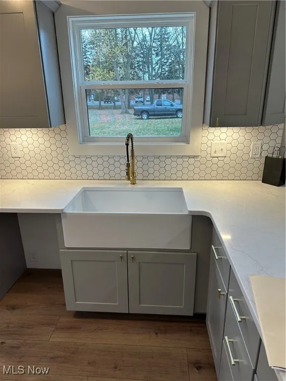 Kitchen view of tasteful backsplash, light stone countertops, and gray cabinets