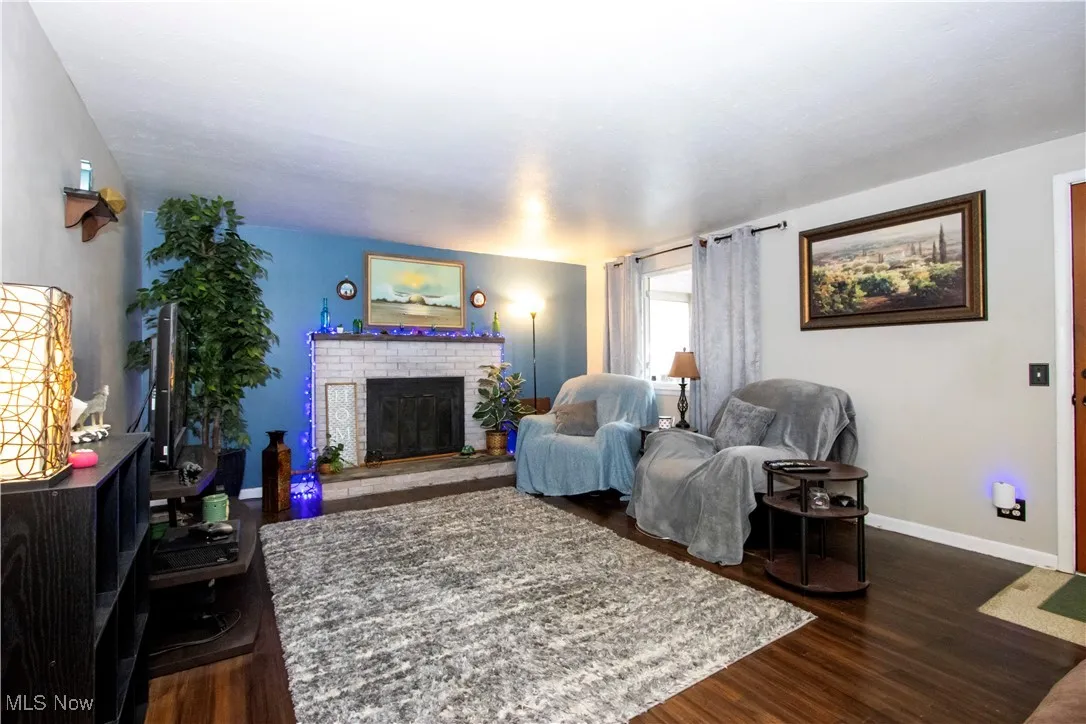 Living room with dark wood-type flooring and a fireplace