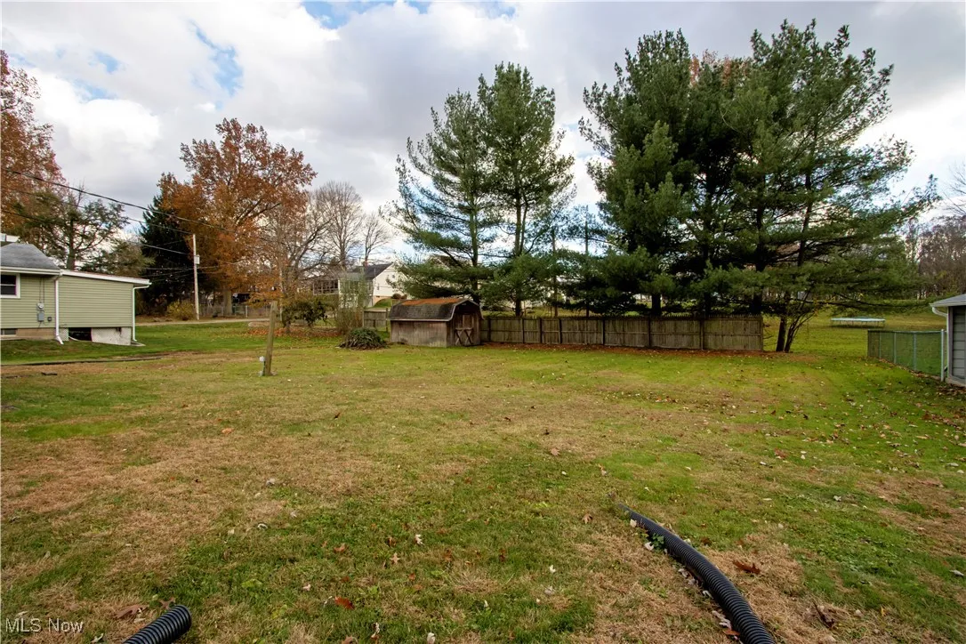 Fenced backyard featuring a shed