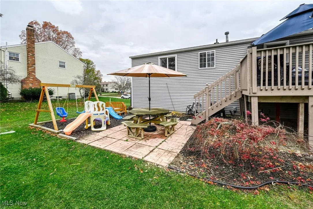 View of green lawn with a patio, deck and storage under deck