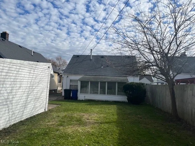 Back of property featuring a lawn and a sunroom