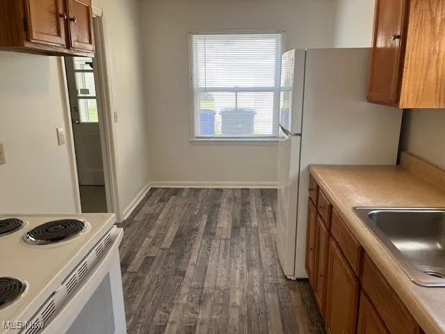 Kitchen with brown cabinetry, healthy amount of natural light, and dark wood-style floors