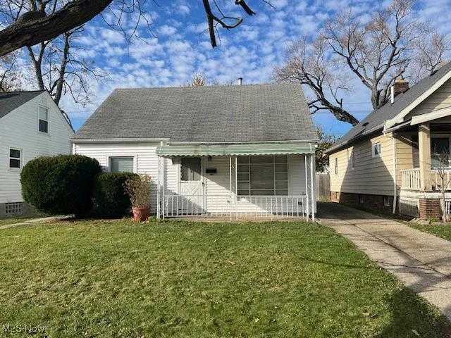 View of front of house with a front yard and a shingled roof
