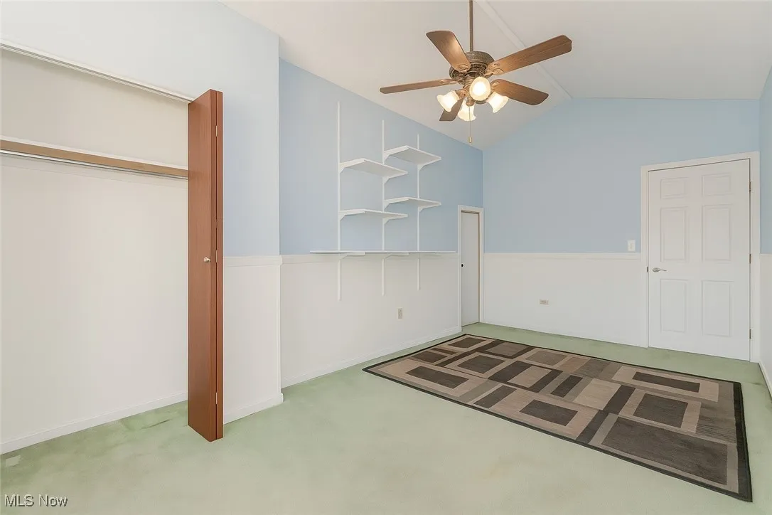 Unfurnished bedroom with lofted ceiling, carpet flooring, and ceiling fan