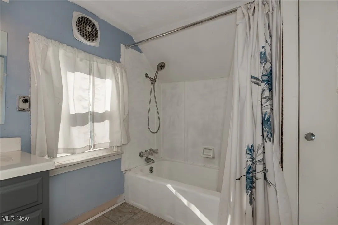 Full bath featuring shower / bath combo with shower curtain, vanity, and light tile patterned flooring