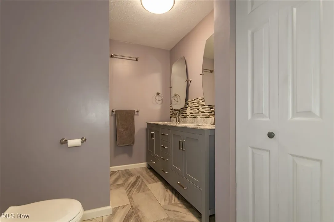 Bathroom featuring backsplash, vanity, a closet, and a textured ceiling