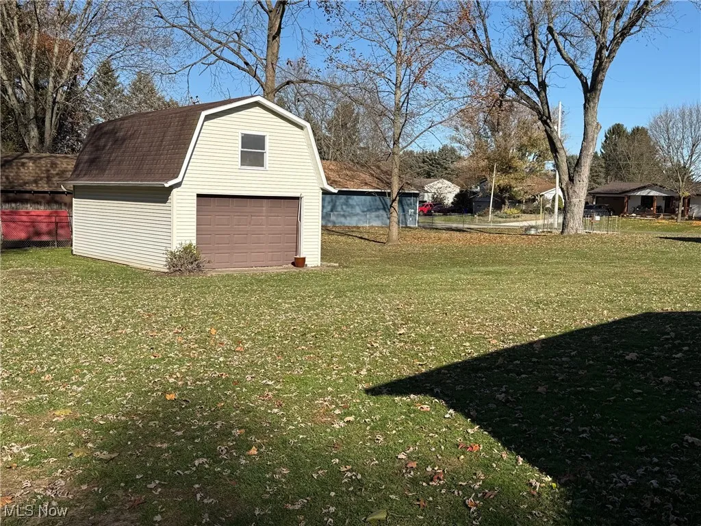 View of green lawn with an outbuilding and a detached garage