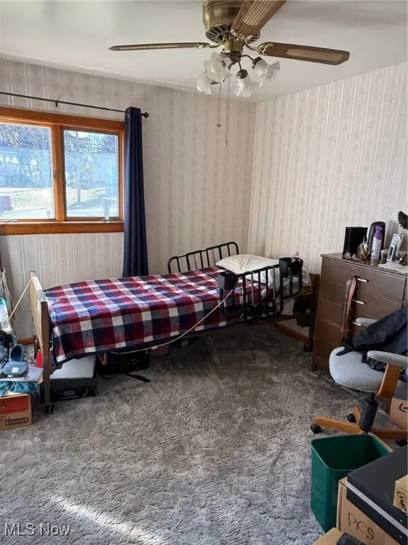 Carpeted bedroom with wallpapered walls and a ceiling fan