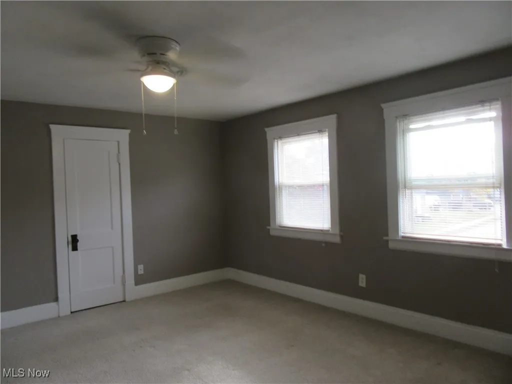 Unfurnished room featuring light carpet and a ceiling fan