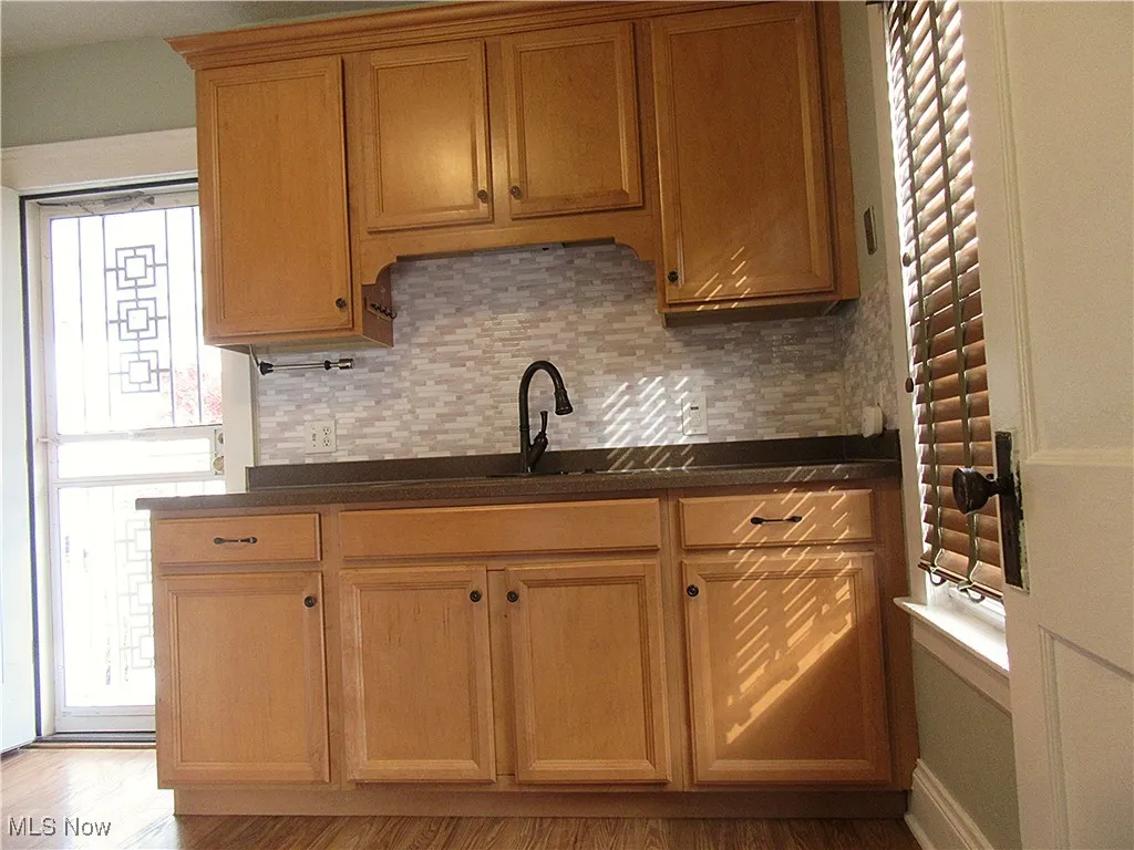 Kitchen with decorative backsplash, light wood-style flooring, and brown cabinetry