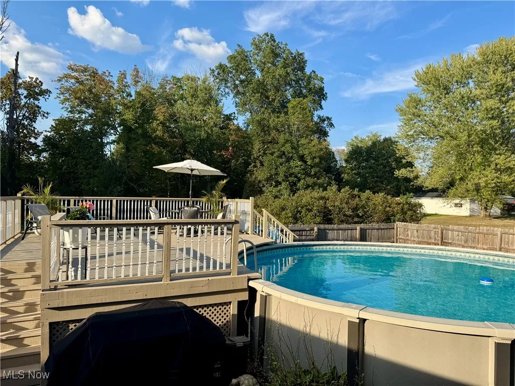 View of swimming pool with a wooden deck and view of scattered trees
