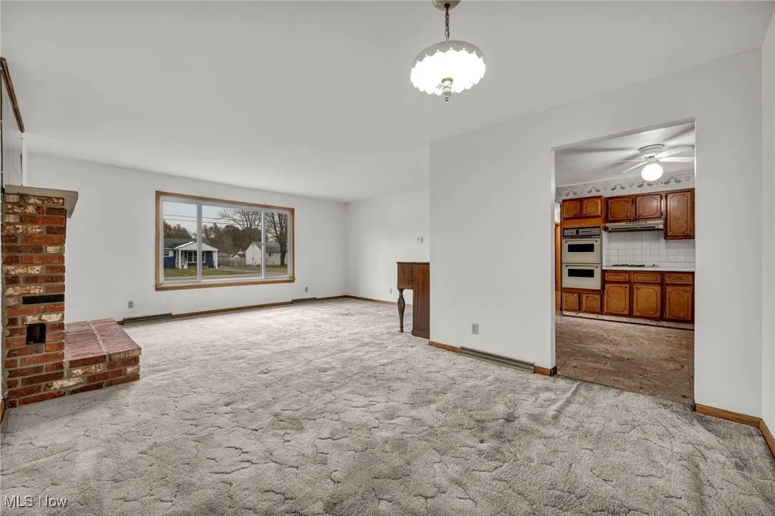 Unfurnished living room with light colored carpet and a ceiling fan