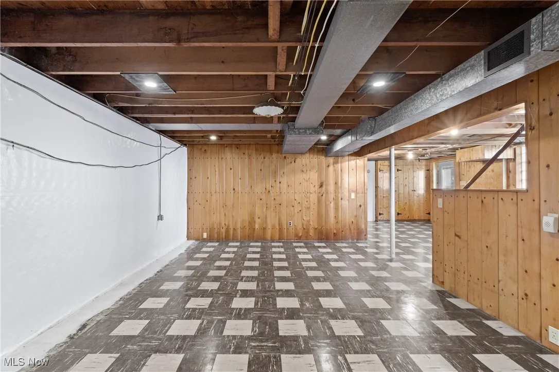 Below grade area with wooden walls and tile patterned floors