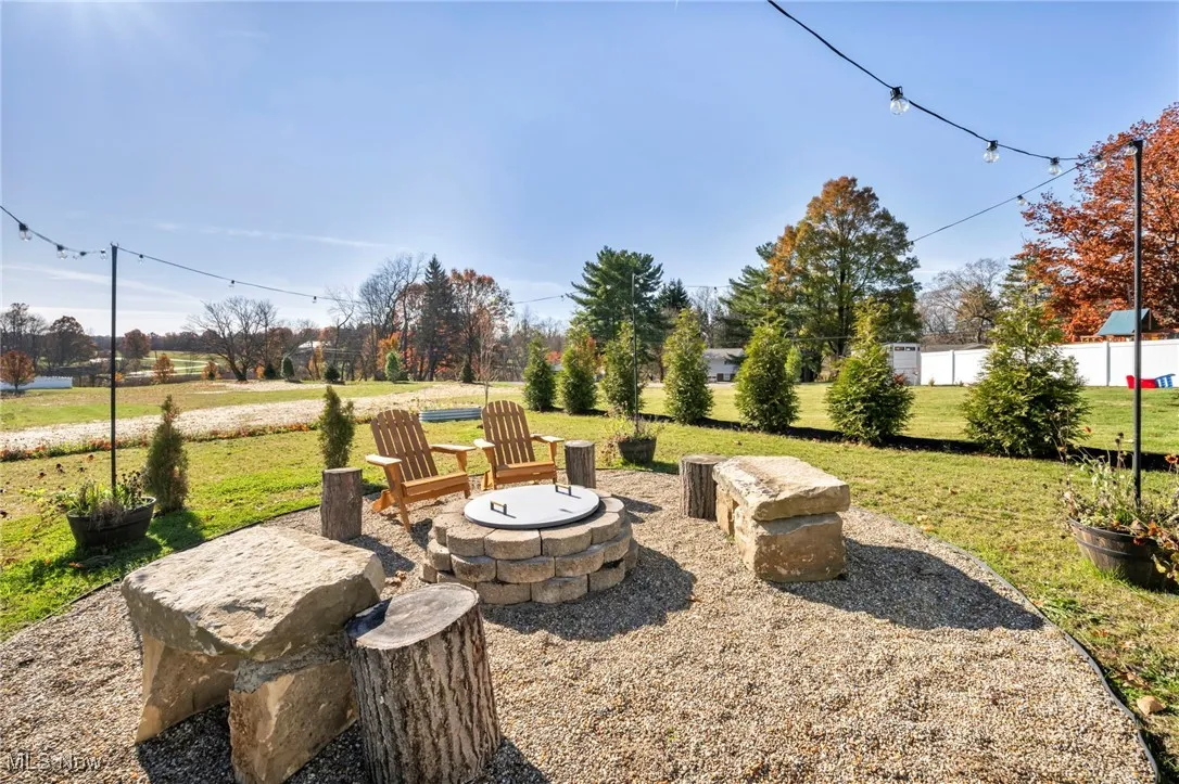 View of green lawn featuring a fire pit and a patio