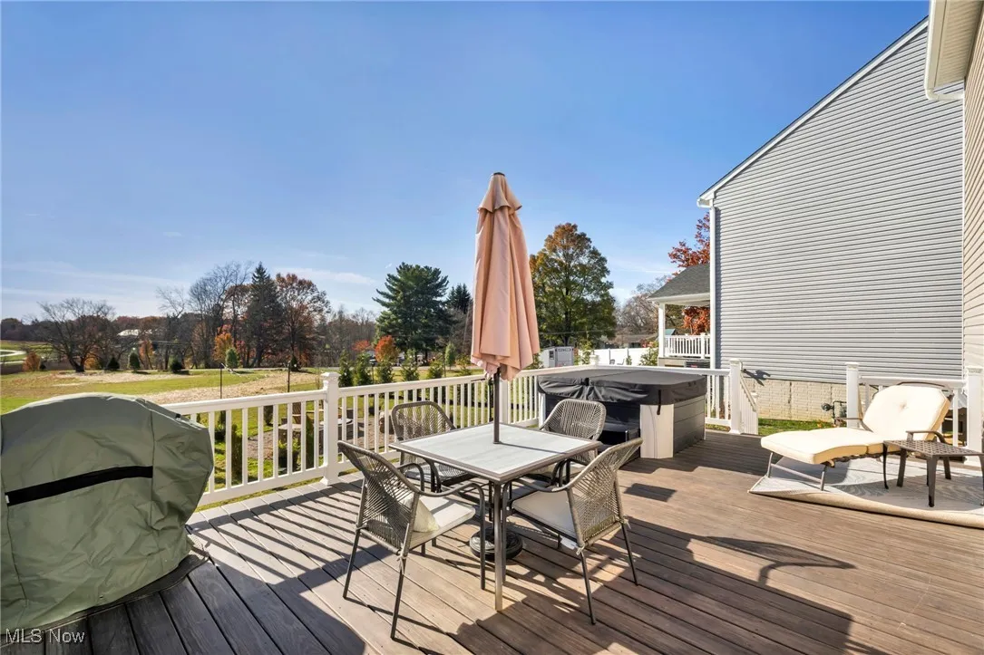 Wooden terrace with outdoor dining space, grilling area, and a hot tub