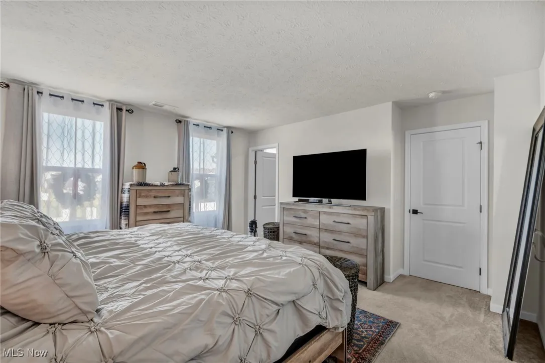 Carpeted bedroom with a textured ceiling and baseboards